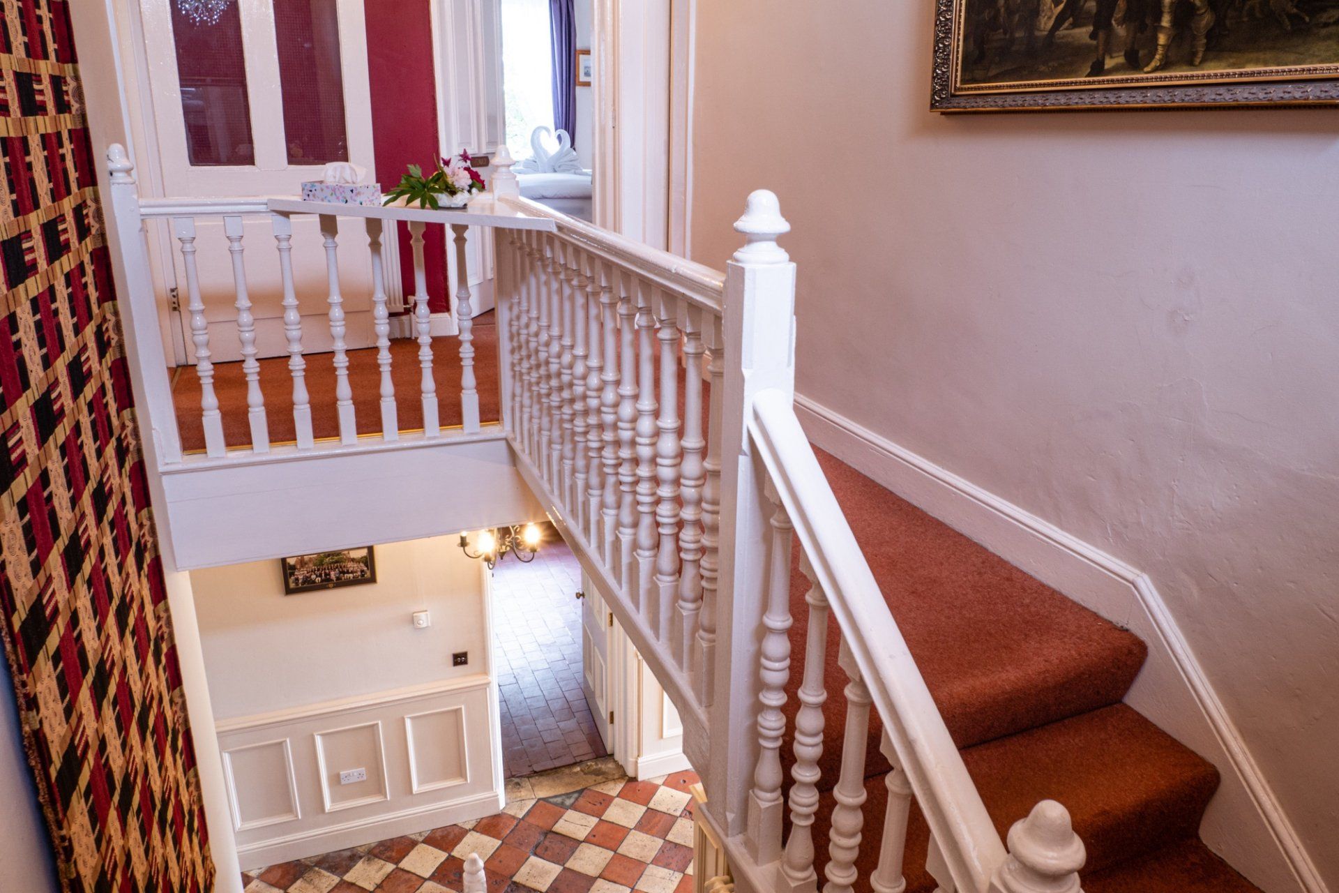 A staircase with a white railing and red carpet