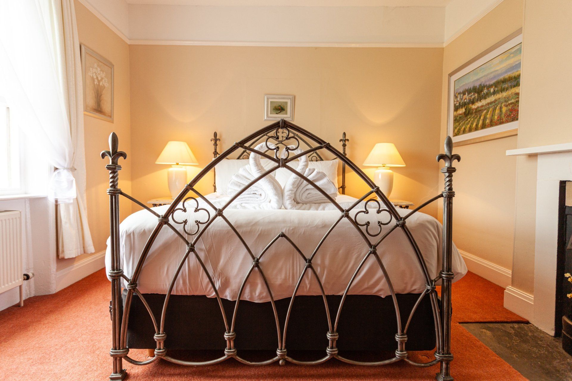 A bedroom with a bed , two lamps and a fireplace.