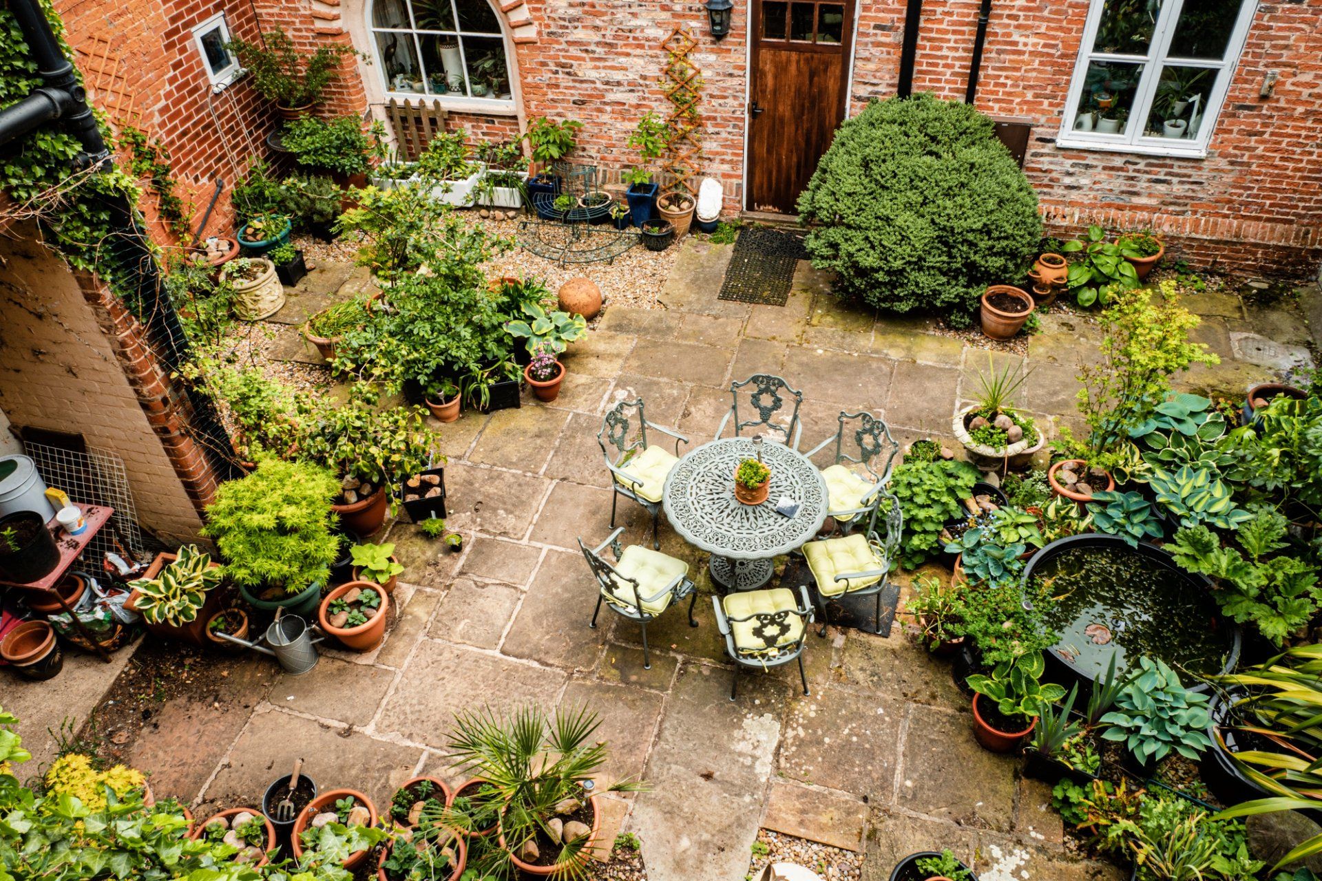 An aerial view of a garden with a table and chairs surrounded by potted plants.