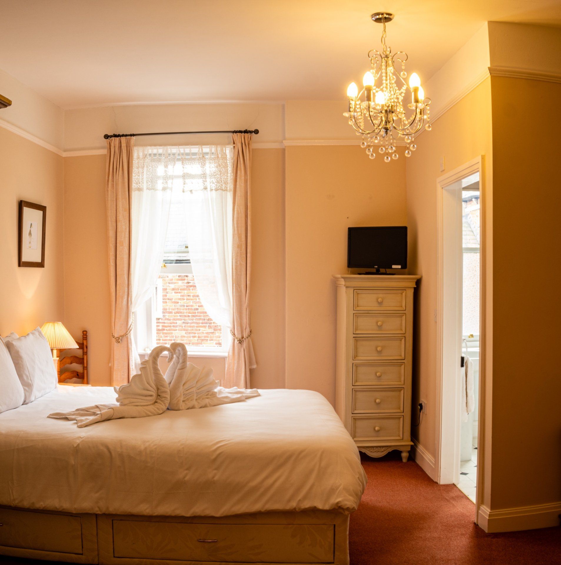 A bedroom with a swan shaped towel on the bed