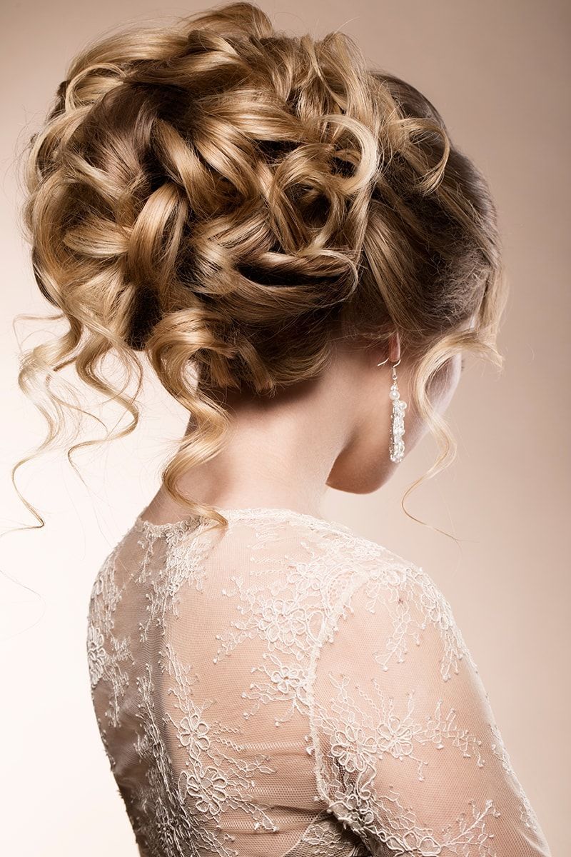 A woman in a white dress is wearing her hair in a bun.