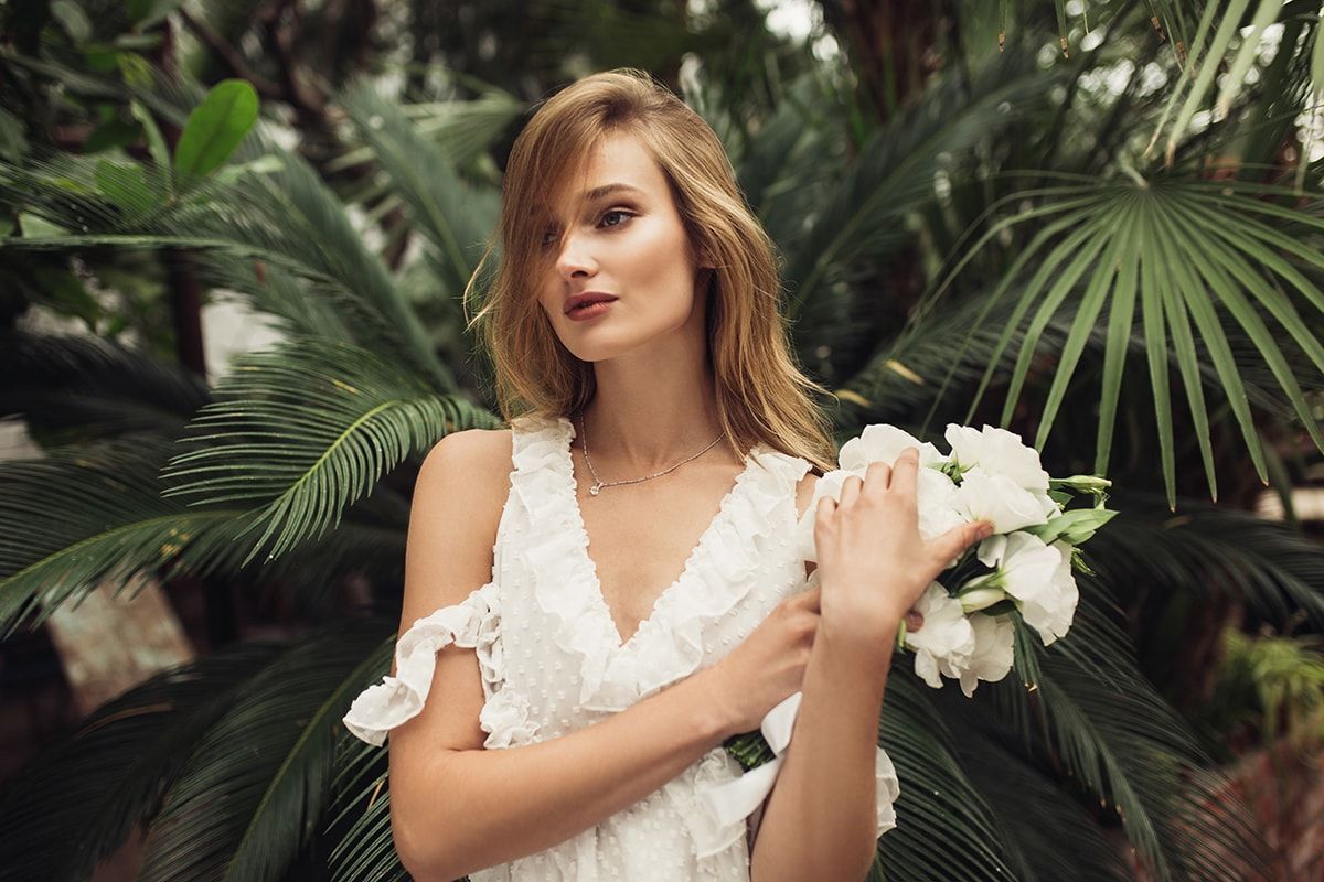A woman in a white dress is holding a bouquet of white flowers.