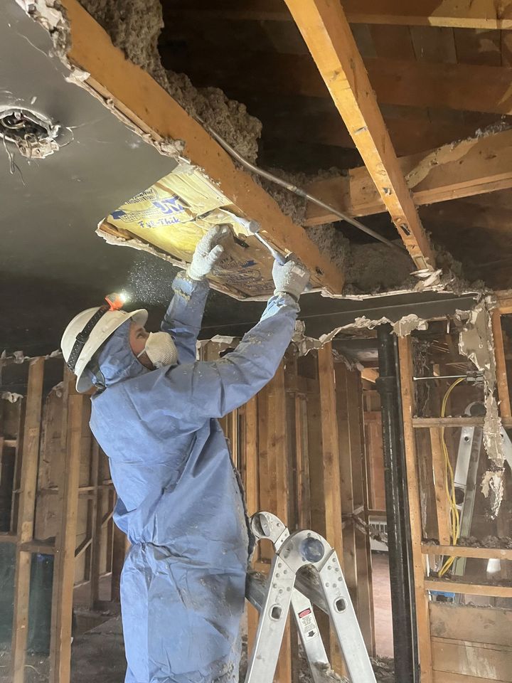 HRS Restoration Services worker in protective gear restoring damaged wall in a Denver Colorado home