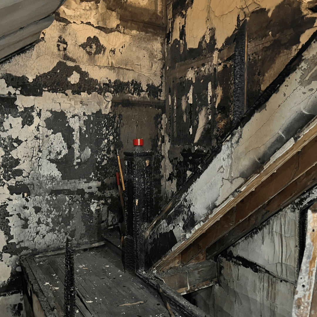 Charred interior of a building, with visible fire damage on walls and wooden beams - HRS Restoration Services.