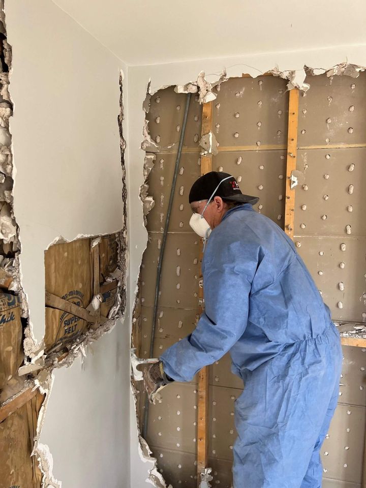 HRS Restoration Services worker in protective gear restoring damaged wall in a Denver Colorado home