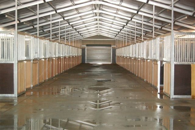 A Large Empty Horse Barn with A Sliding Door — ShedPro Constructions in Darawank, NSW
