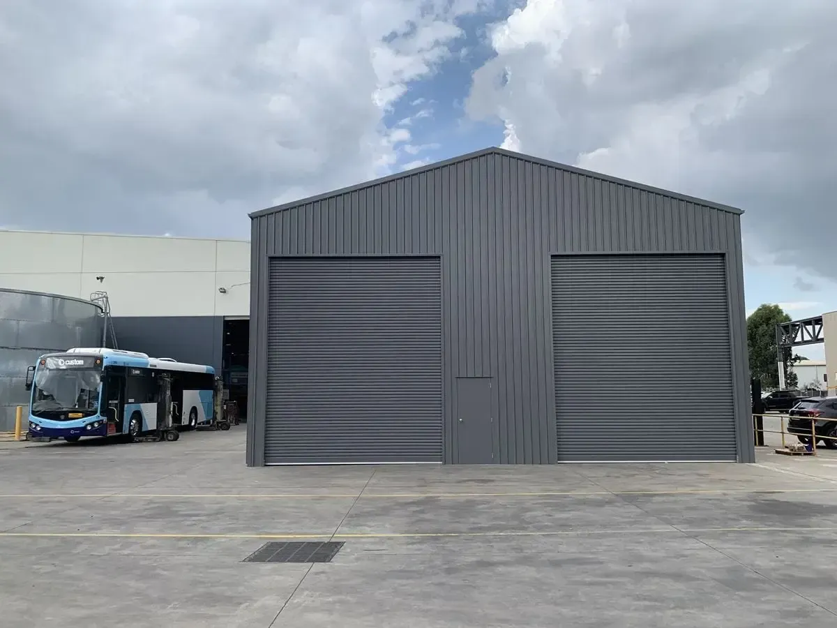 A Bus is Parked in Front of a Large Building — ShedPro Constructions in Darawank, NSW
