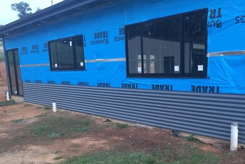 A Building With a Blue Tarp on the Side of It — ShedPro Constructions in Bulahdelah, NSW