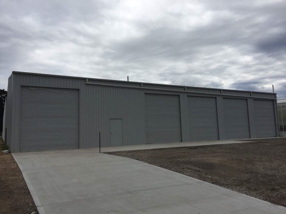 A Large Gray Building with A Lot of Garage Doors — ShedPro Constructions in Darawank, NSW