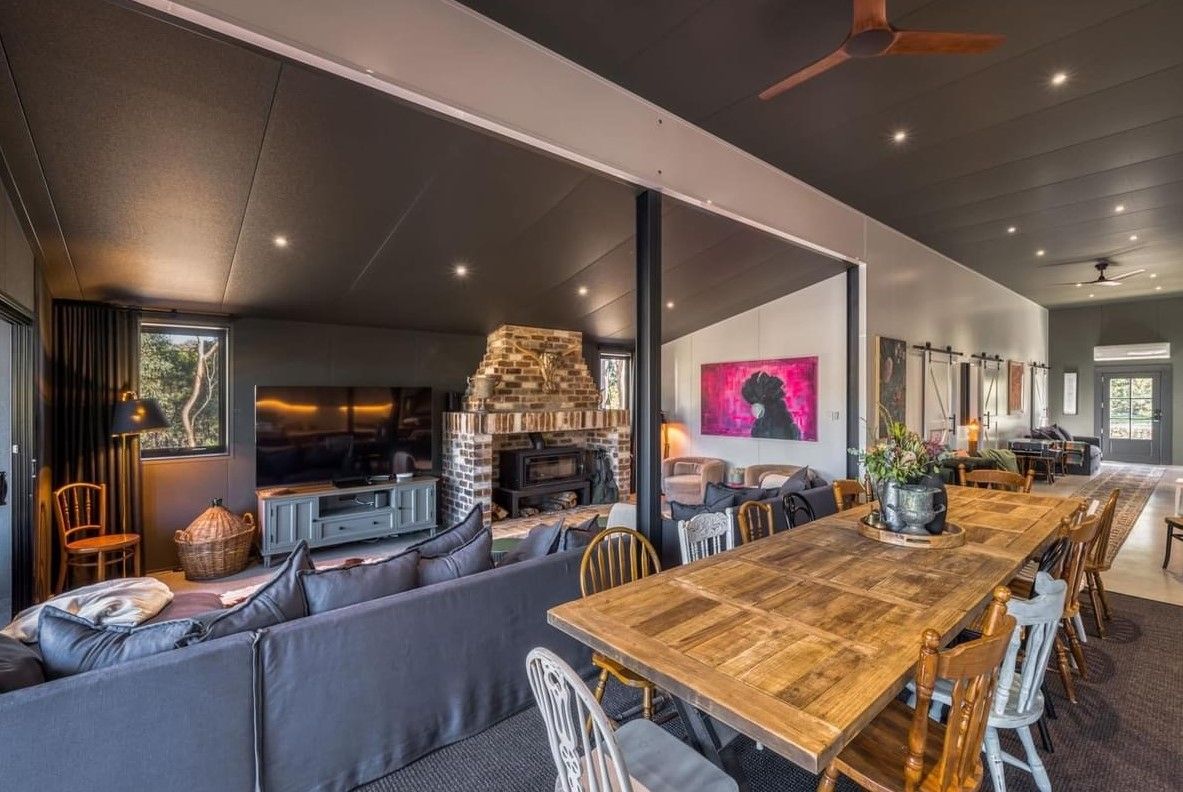 A Living Room With a Long Wooden Table and Chairs and a Fireplace — ShedPro Constructions in Raymond Terrace, NSW
