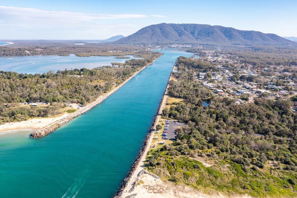An Aerial View of a River Surrounded by Trees and Mountains — ShedPro Constructions in Mid North Coast, NSW