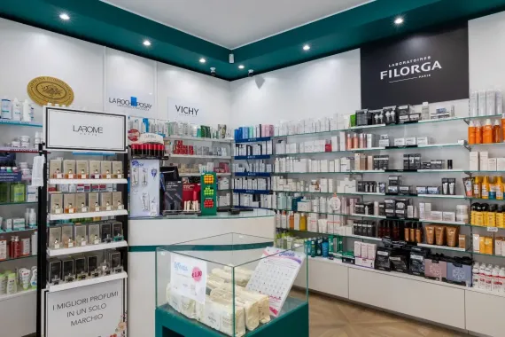 Due donne esaminano una bottiglia verde nel corridoio di un negozio di cosmetici.