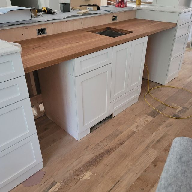 a kitchen with white cabinets and a wooden counter top