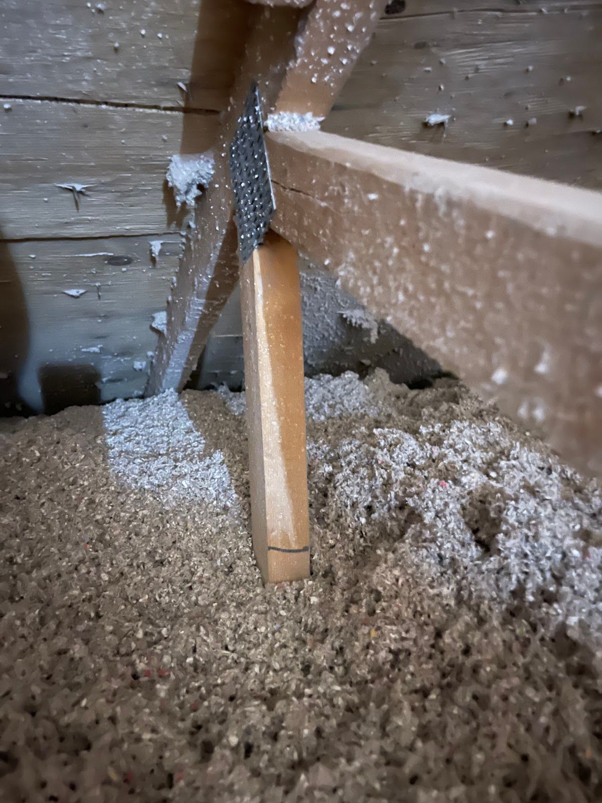 Wooden support beam with insulation in an attic.