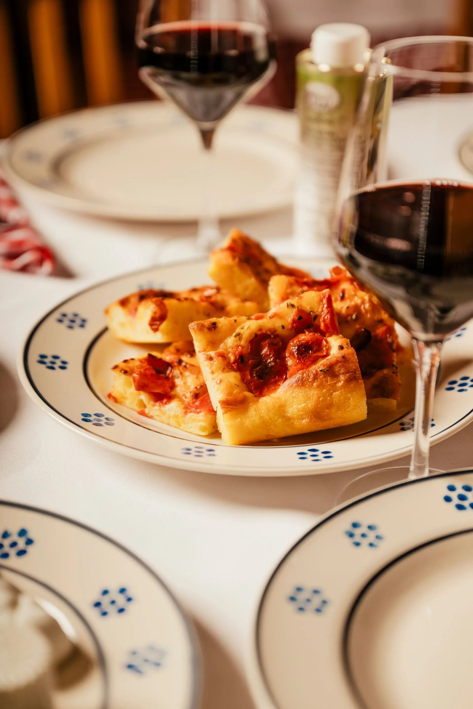Piatti da dessert con fette di torta e bicchieri da vino rosso su un tavolo bianco da ristorante.