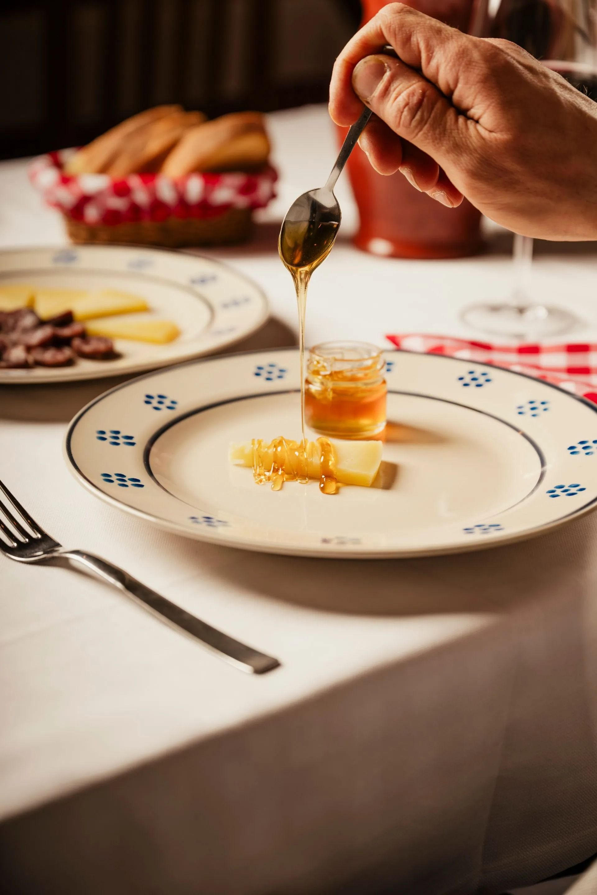 Versare a mano il miele su un piccolo dessert su un piatto bianco a un tavolo da pranzo.