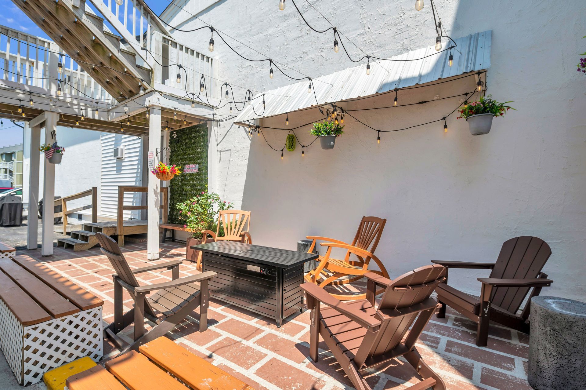 Outdoor patio with brick floor, wooden chairs, and string lights.
