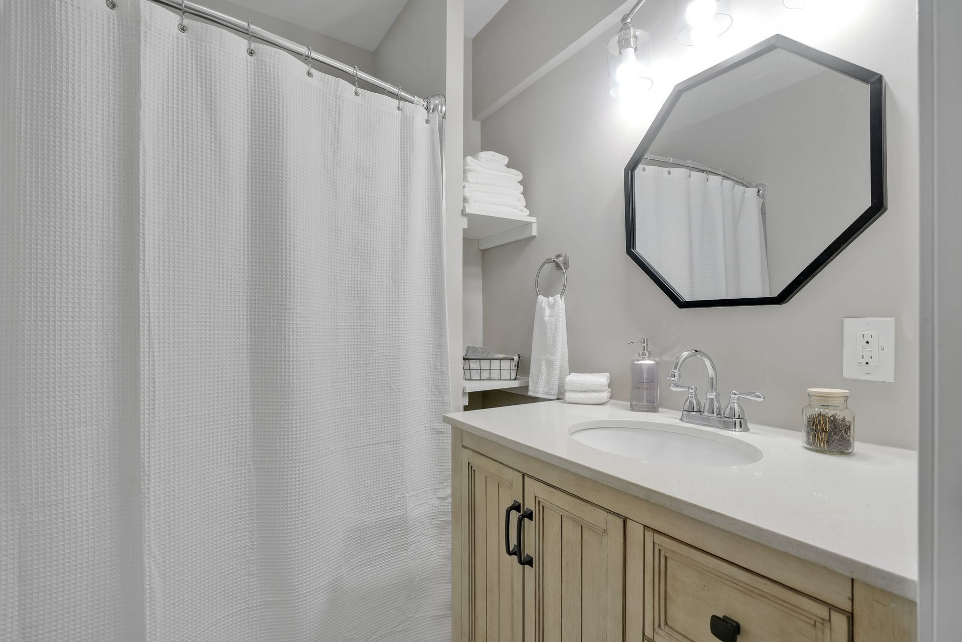 Bathroom with white shower curtain, vanity, mirror, and towels.