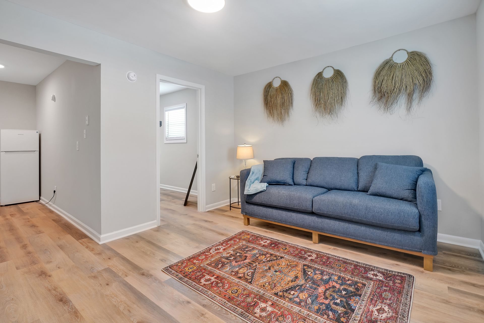 Living room with blue sofa, rug, and wall decorations.
