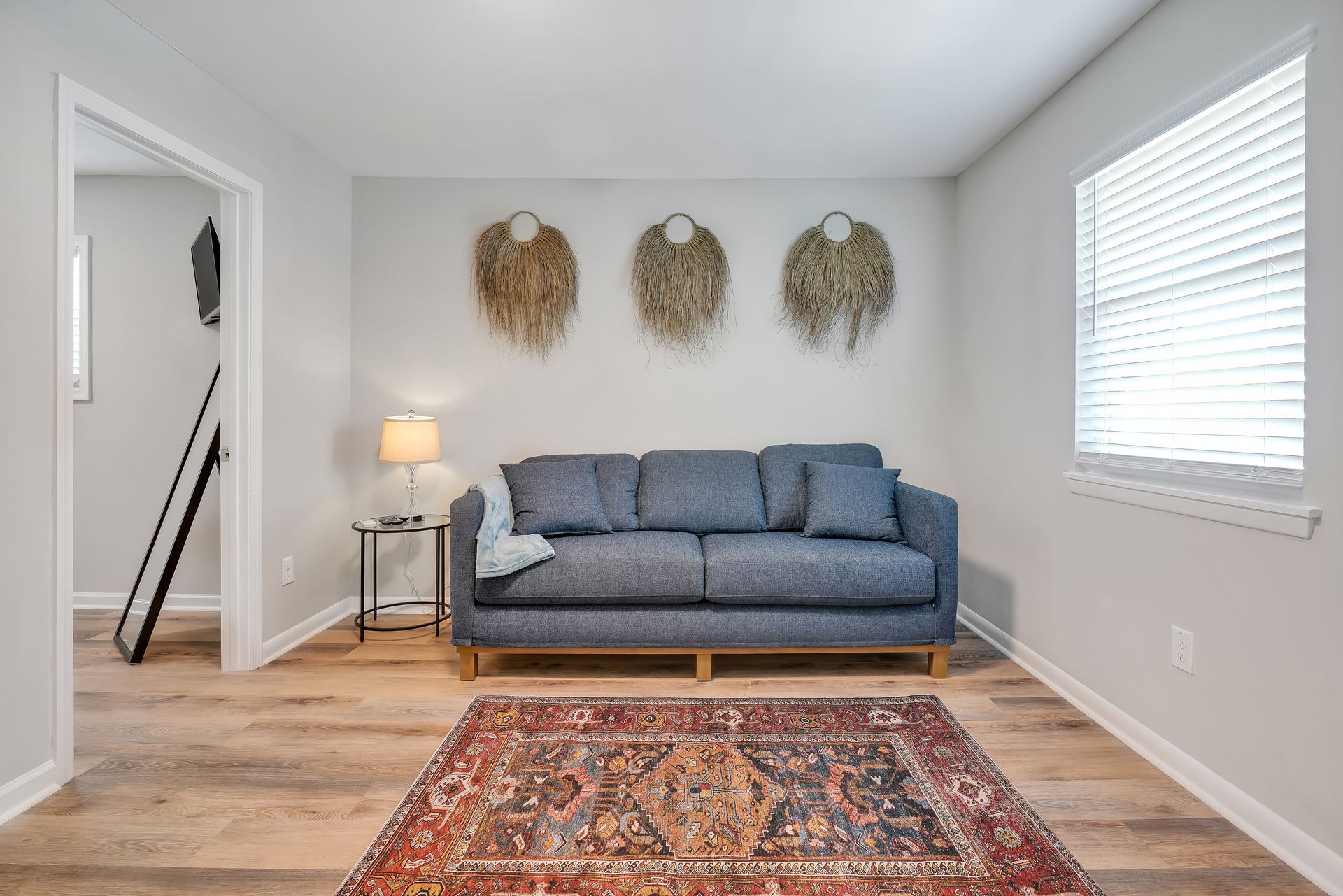 Cozy living room with a blue sofa, rug, and decorative wall hangings.