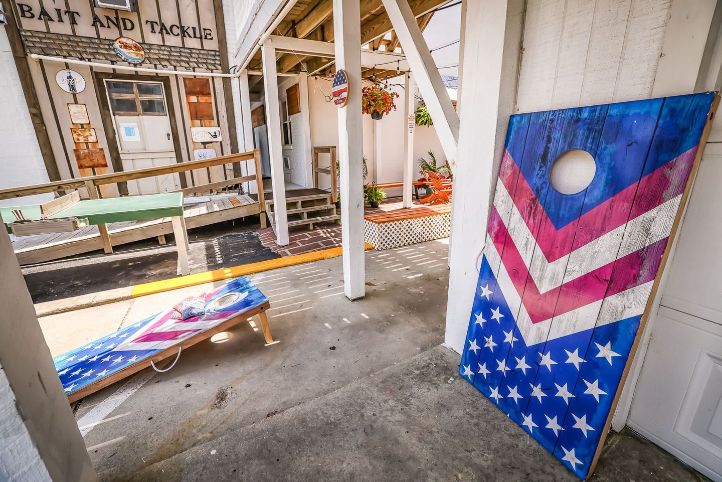 Two cornhole boards with American flag designs, one standing, the other on the ground in an outdoor setting.