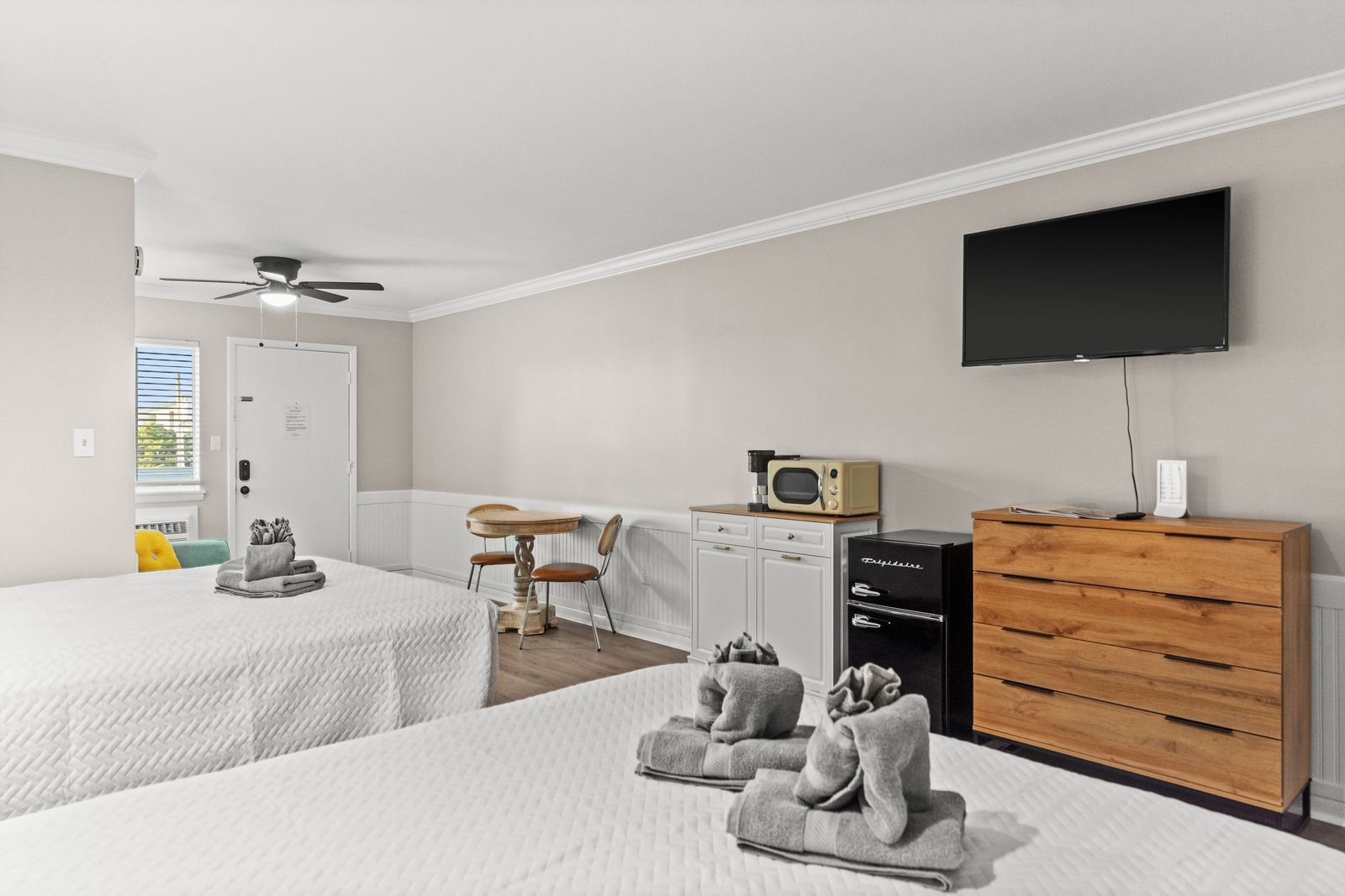 Studio apartment with white walls, bed, kitchenette, TV, and table.