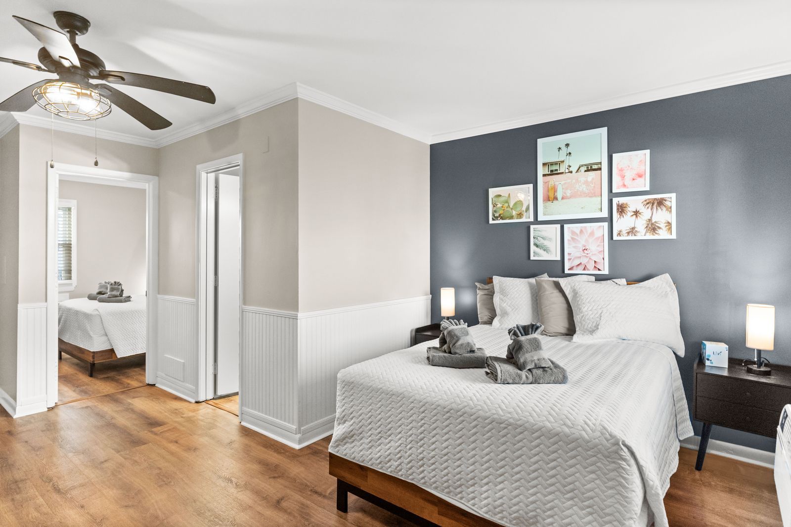 Bedroom with a bed, artwork, and a doorway to another bedroom with a bed.