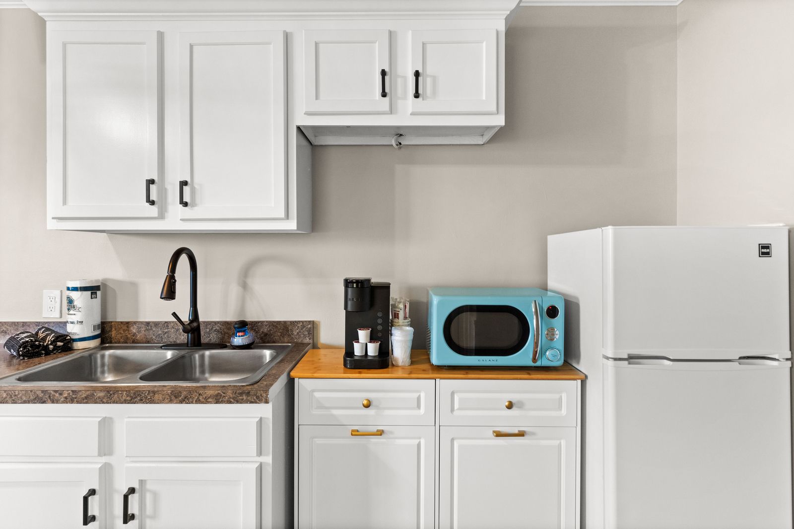Small kitchen with white cabinets, light blue microwave, and white refrigerator.