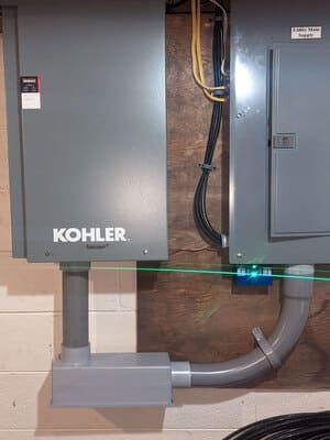 Kohler backup generator connected to electrical panels with conduit and wiring outdoors