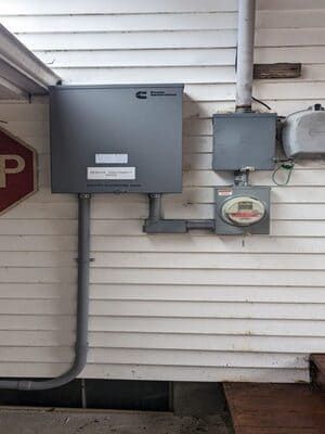 Gray utility boxes and electrical meter mounted on the exterior wall of a house