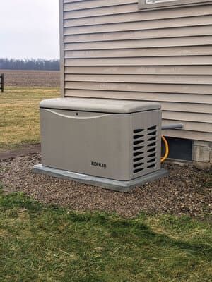 Outdoor home standby generator beside a beige house on a grassy lawn