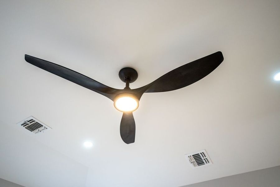 Black ceiling fan with light on a white ceiling