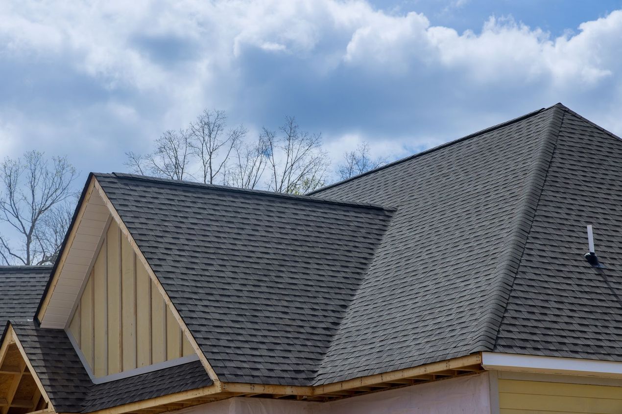 Brown roof with matching gutters and downspout on a white building, against a blue sky.