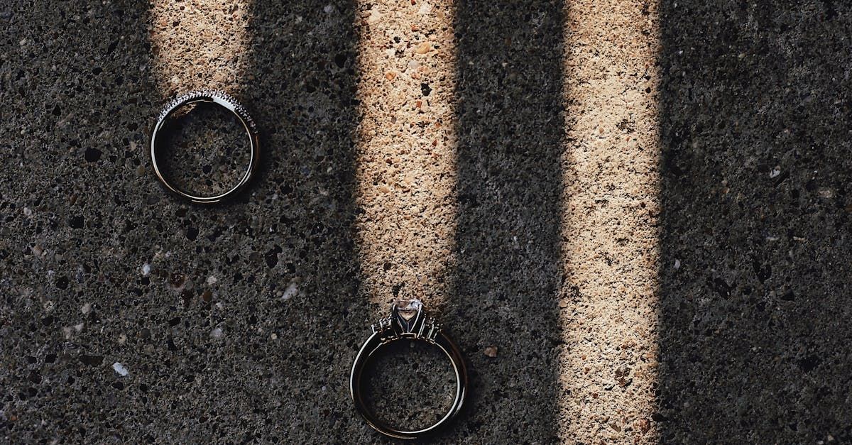 Two metal rings on dark, textured surface with light-colored stripes.