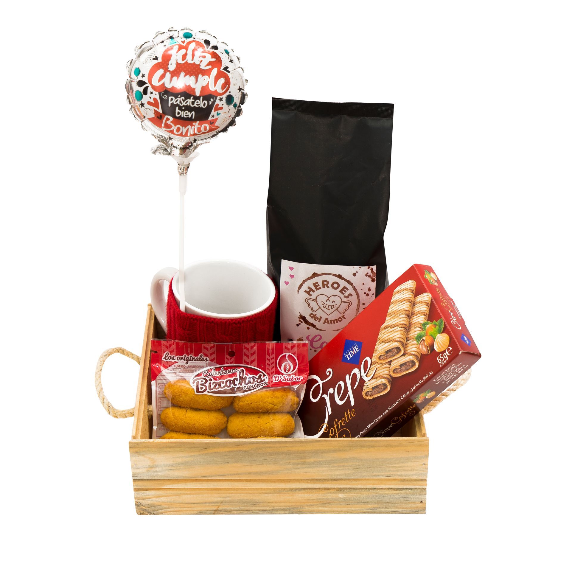 Cesta de regalo con taza roja, piruleta, bolsitas de aperitivos y dulces variados en una caja de madera.