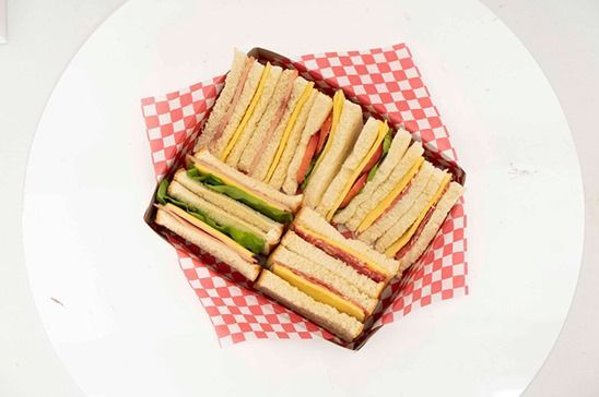 Sándwiches variados en una servilleta a cuadros rosa sobre un plato blanco.