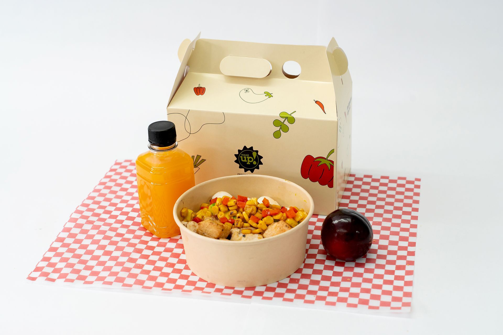 Comida para llevar con bebida de naranja, tazón de comida y un pequeño condimento sobre un mantel a cuadros.