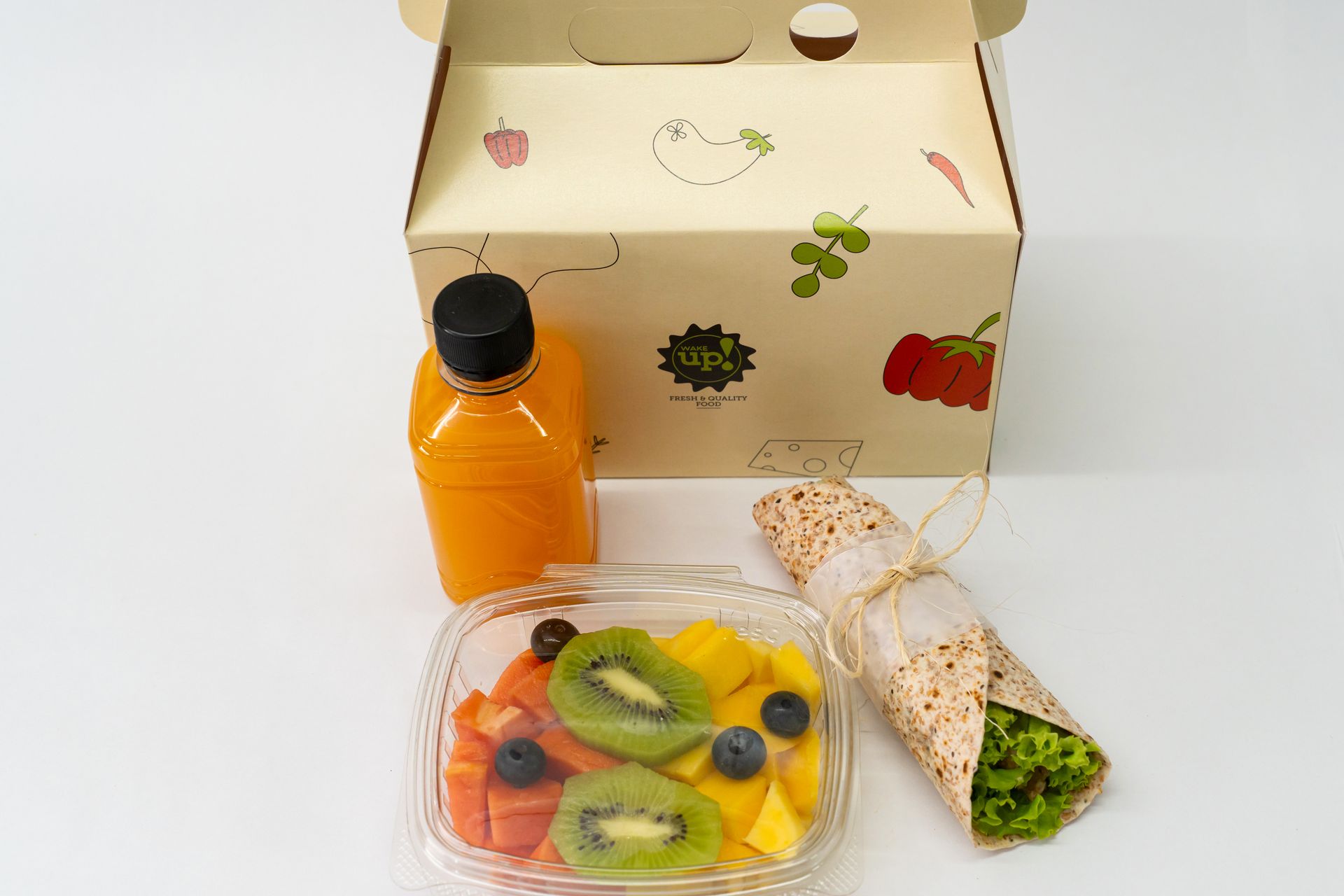 Caja de regalo con bebida de naranja, bandeja de frutas y dos envoltorios sobre una superficie blanca.