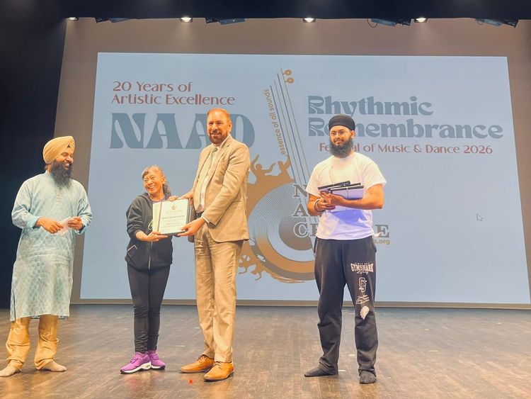 Four people stand on a stage during a music education event, with a large “Rhythmic Renaissance” backdrop.