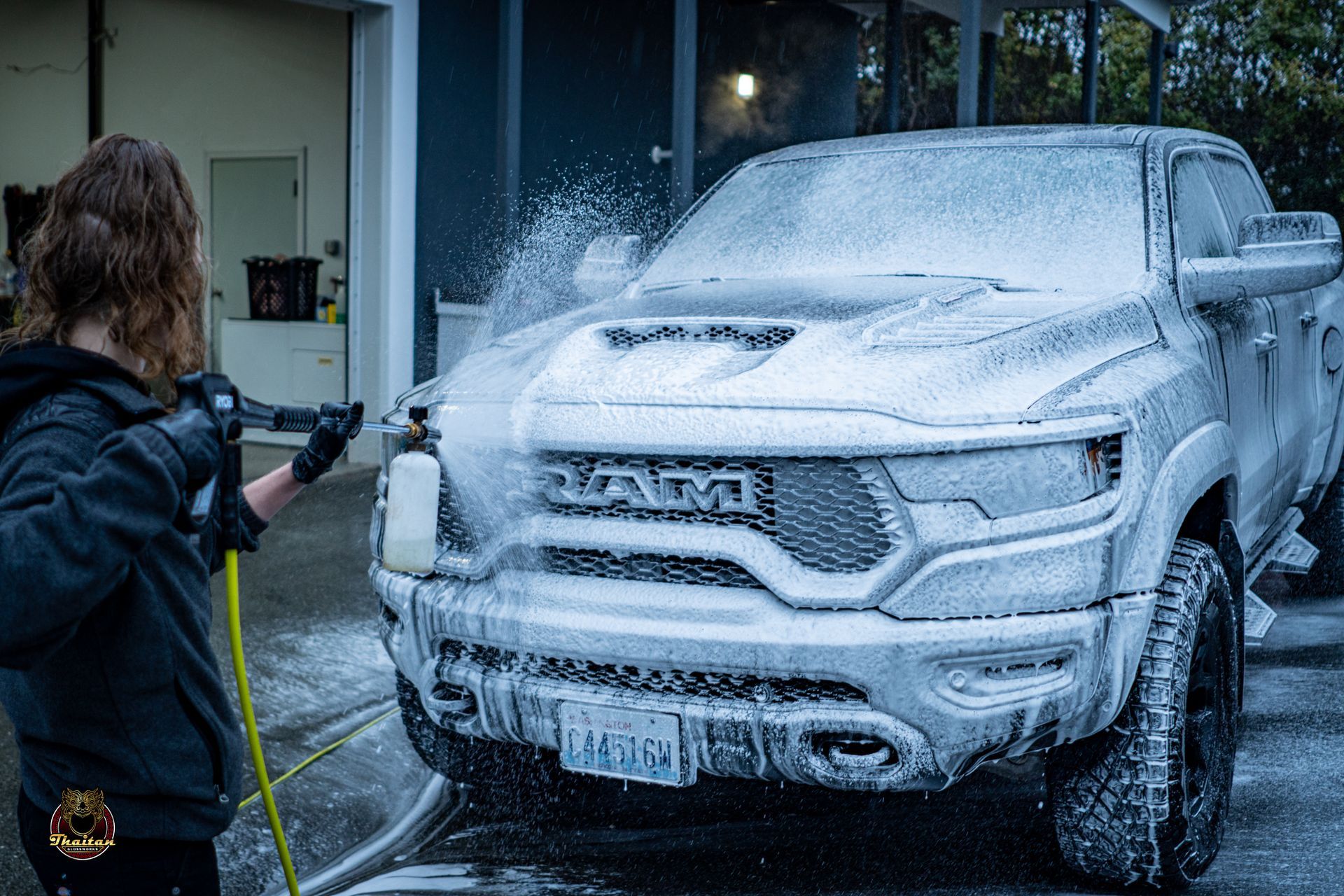 A woman is washing a ram truck with foam.