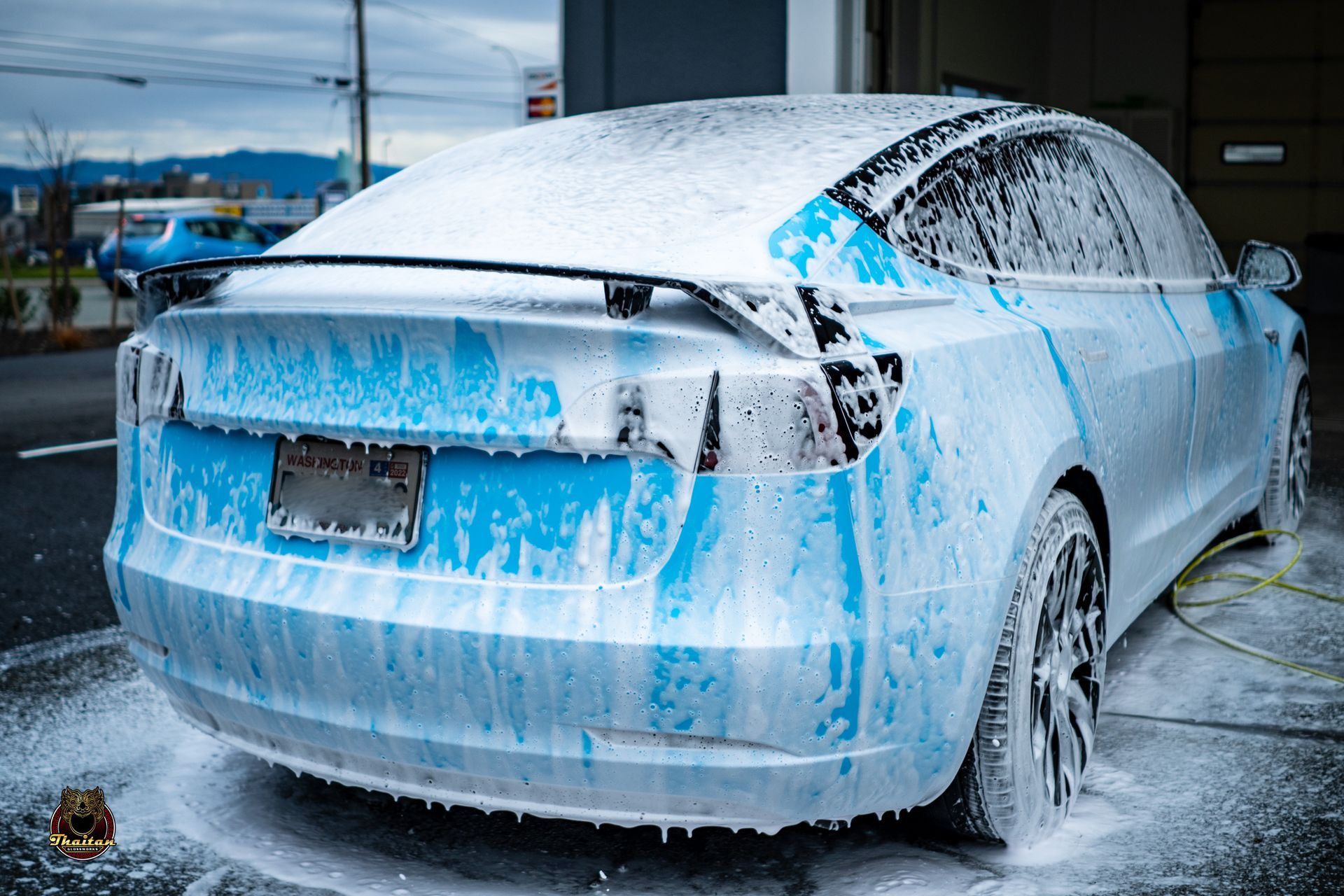A white tesla model 3 is covered in foam.