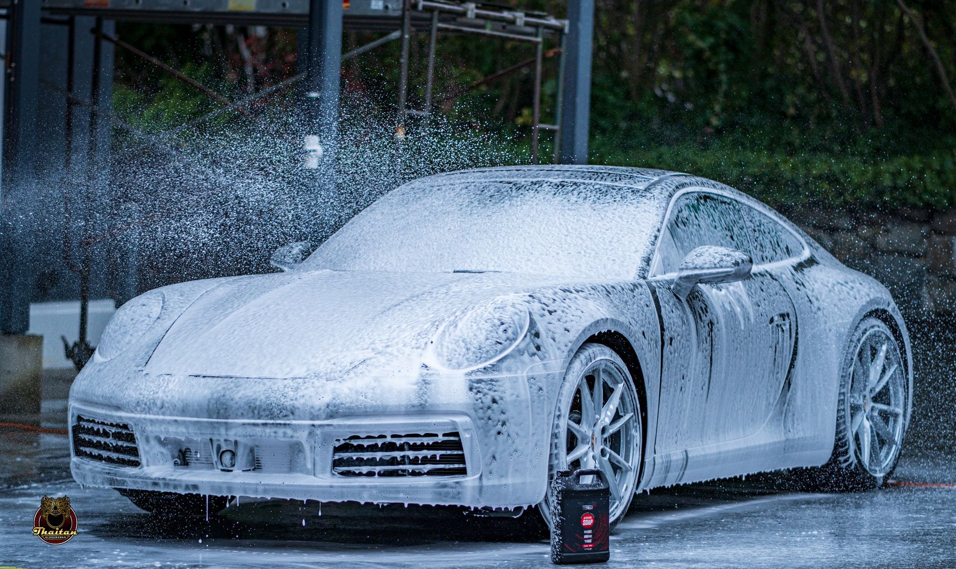 A porsche 911 is covered in foam at a car wash.