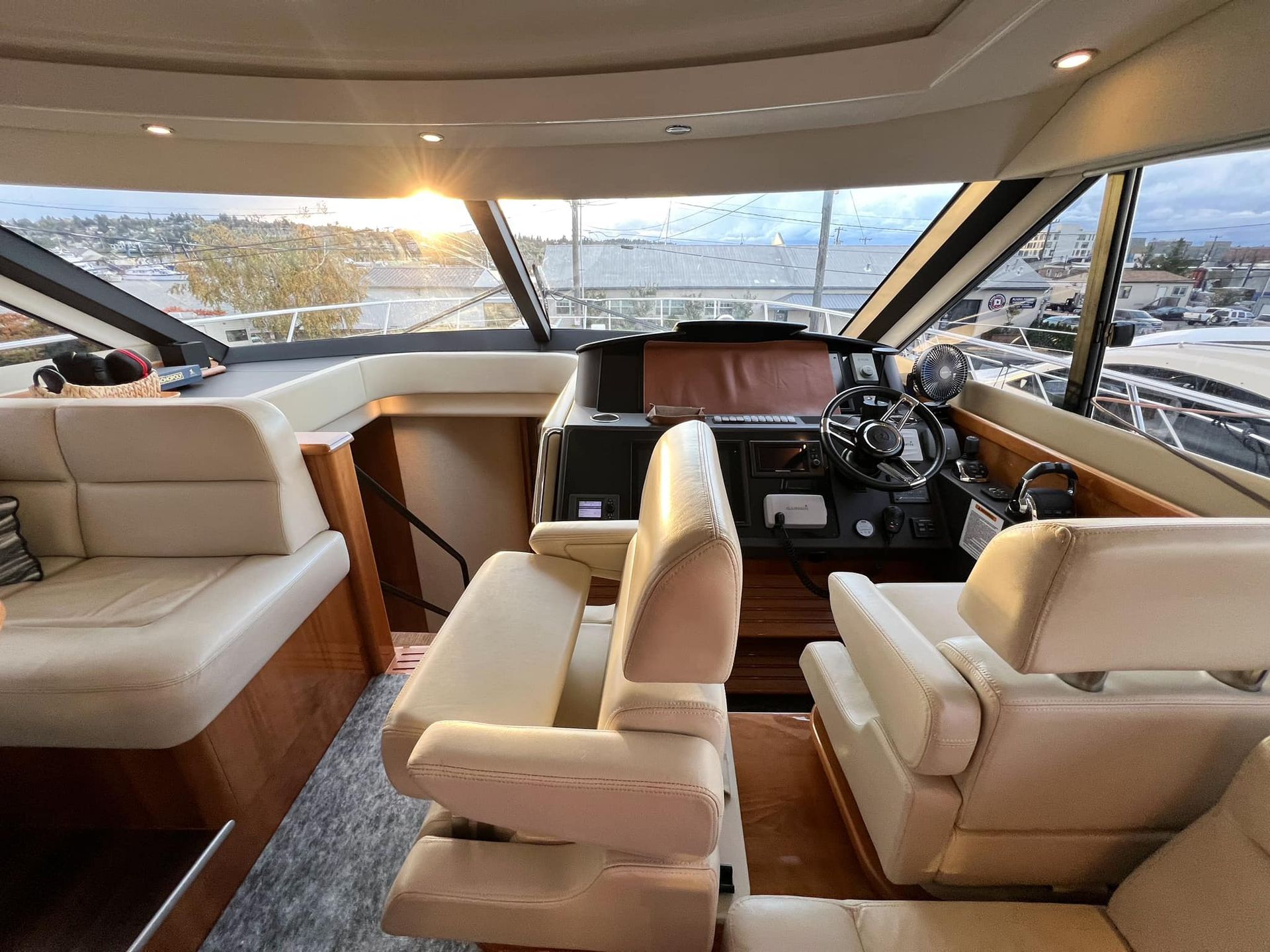 The inside of a boat with a steering wheel and chairs.