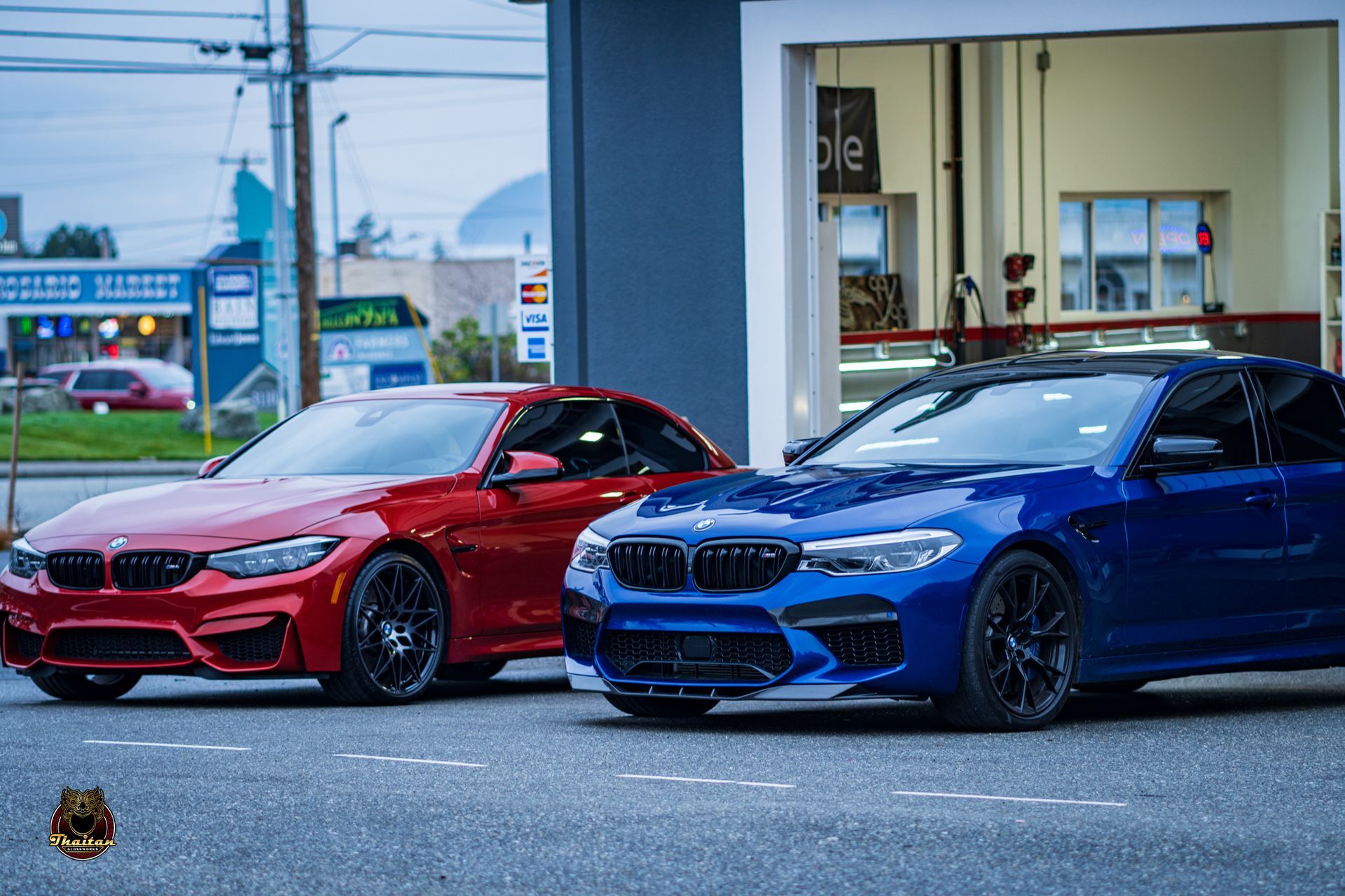 Red and blue BMW cars parked at a gas station.