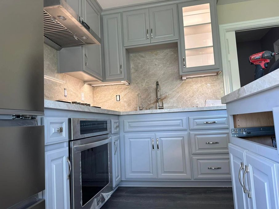 White kitchen with cabinets, stove, sink, and marble-pattern backsplash in daylight