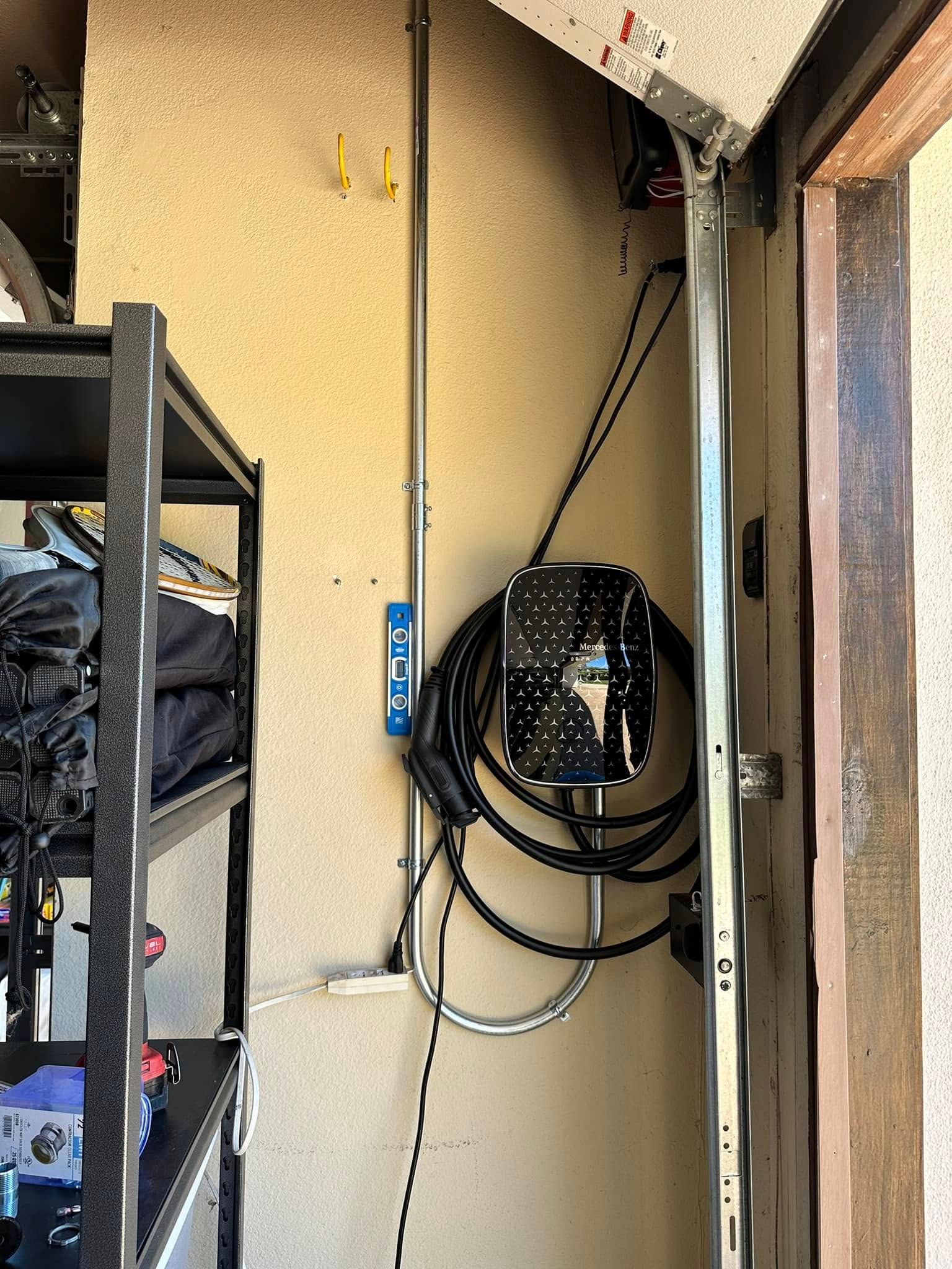 Utility closet with shelves, coiled cables, and a wall-mounted black backpack or equipment bag.