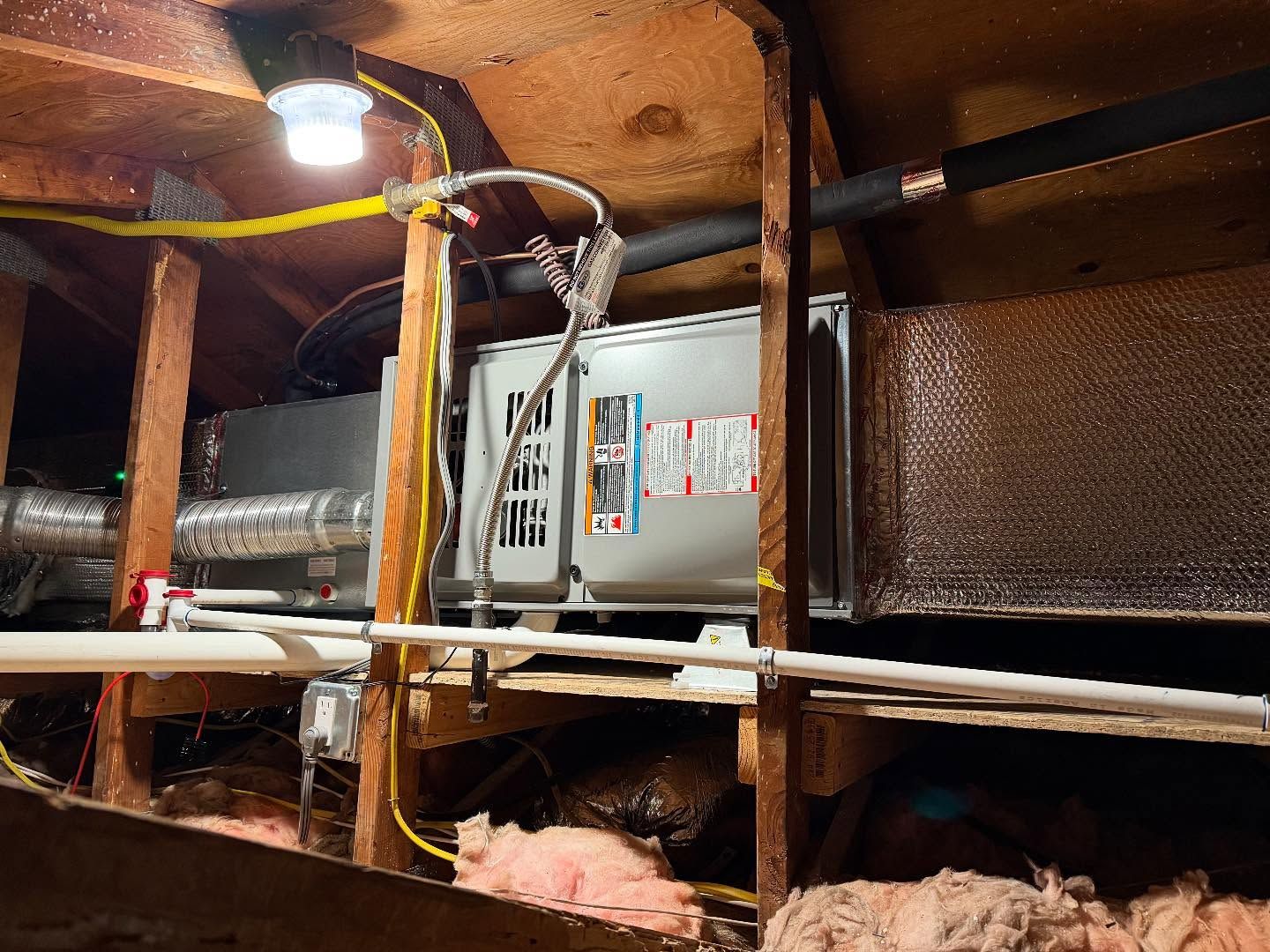 HVAC unit and ductwork inside a cramped crawlspace with exposed framing and insulation
