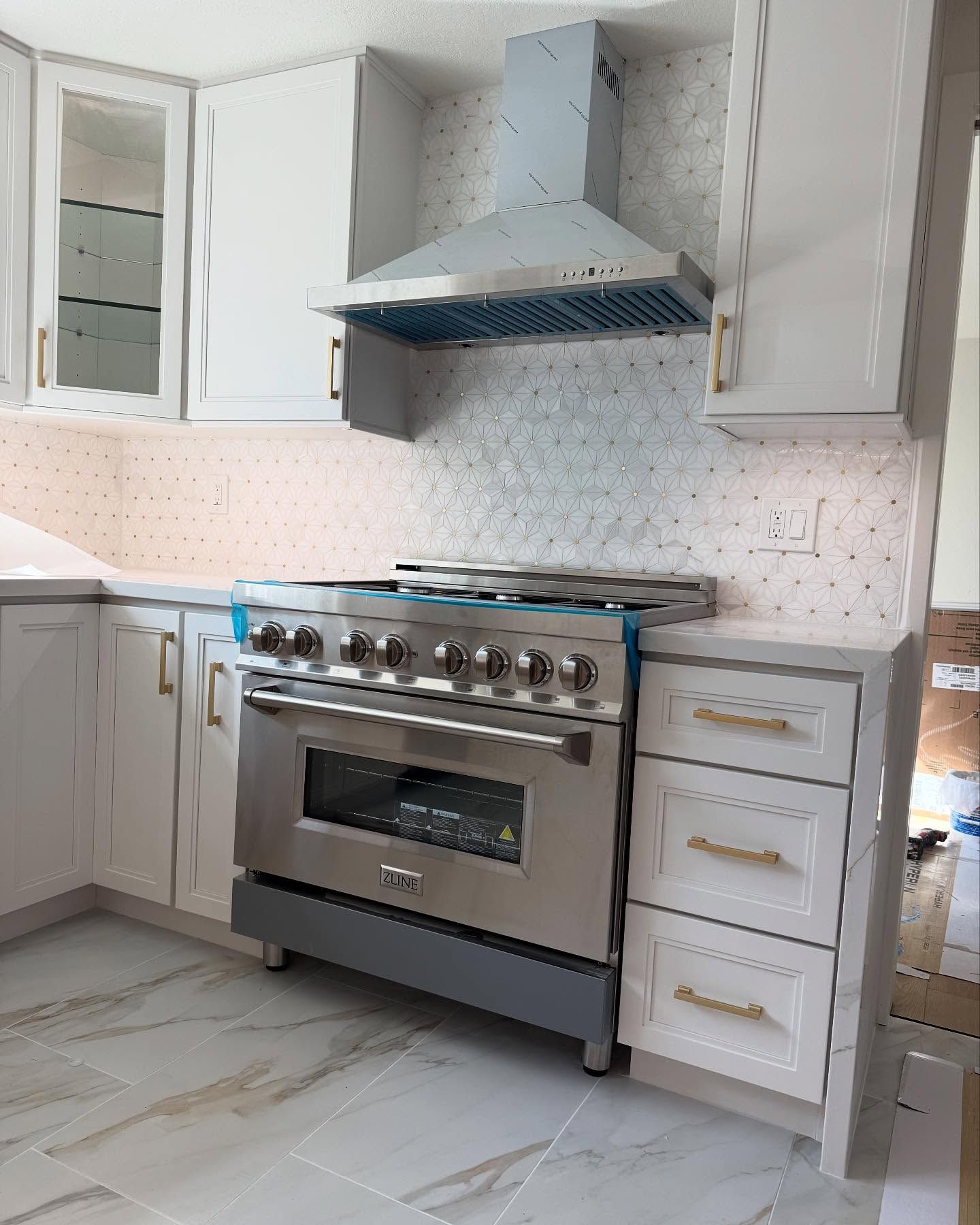 Modern white kitchen with stainless steel stove, range hood, and white cabinetry