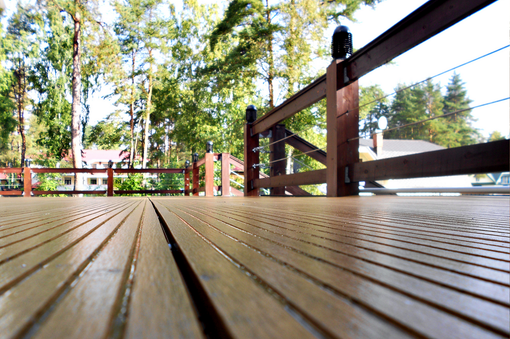 A wooden deck with a fence and trees in the background A wooden deck with a fence and trees in the background