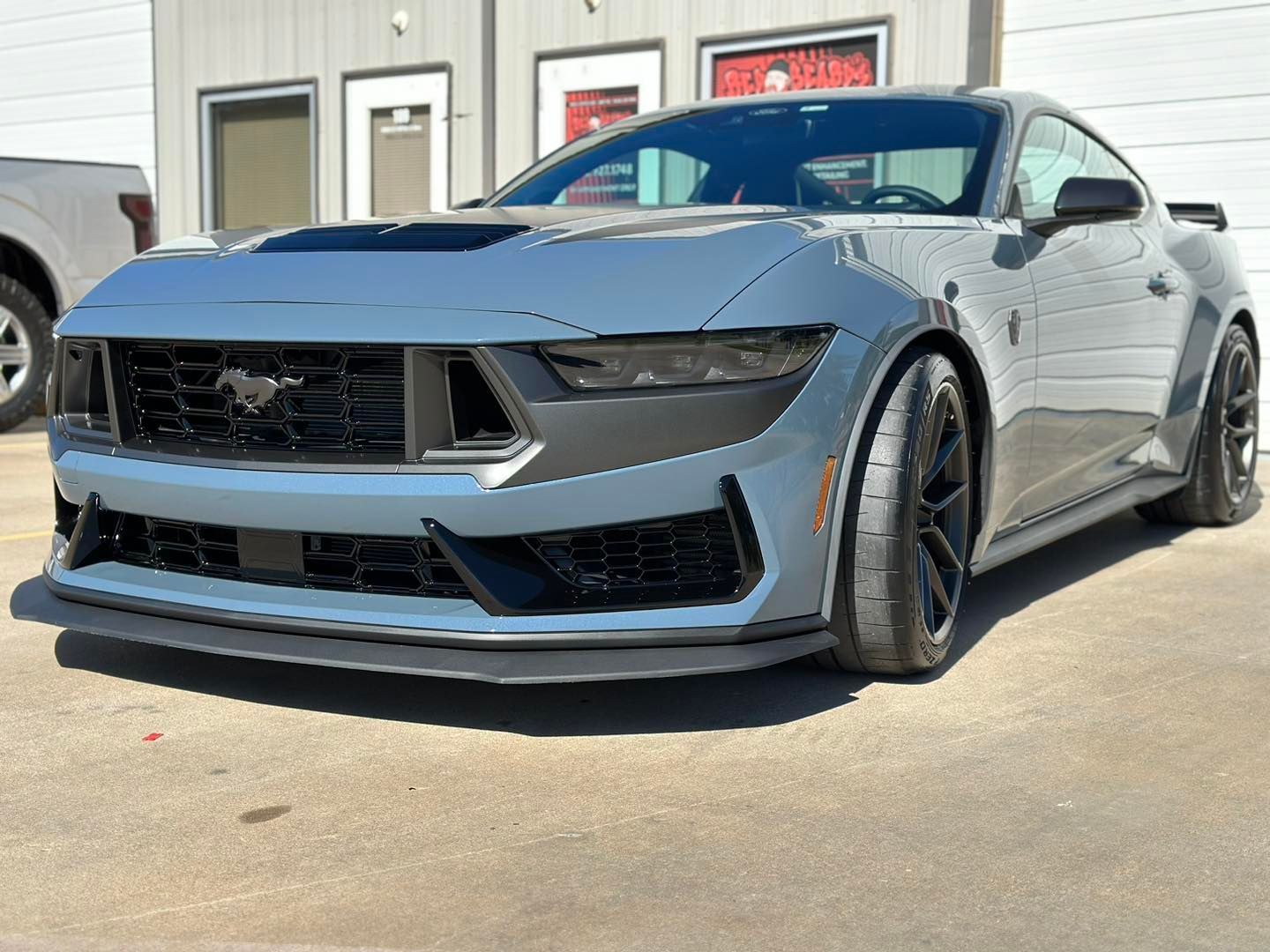 A gray mustang is parked in front of a building.